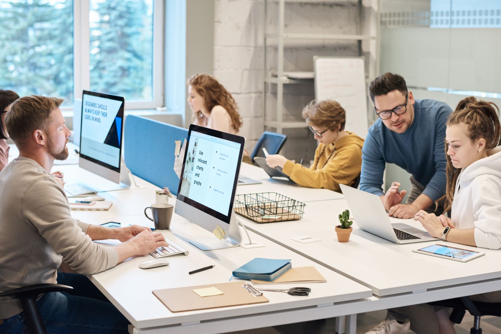 Des collègues travaillent sur leurs ordinateurs autour d'une table dans un bureau lumineux